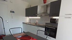 Ett modernt kök med ett matbord, stolar, en mikrovågsugn och en ugn.