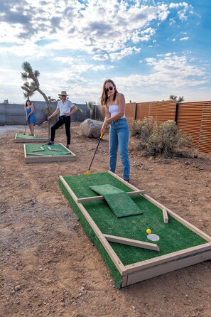 A mini-golf setup with two players and a golf ball on the course.