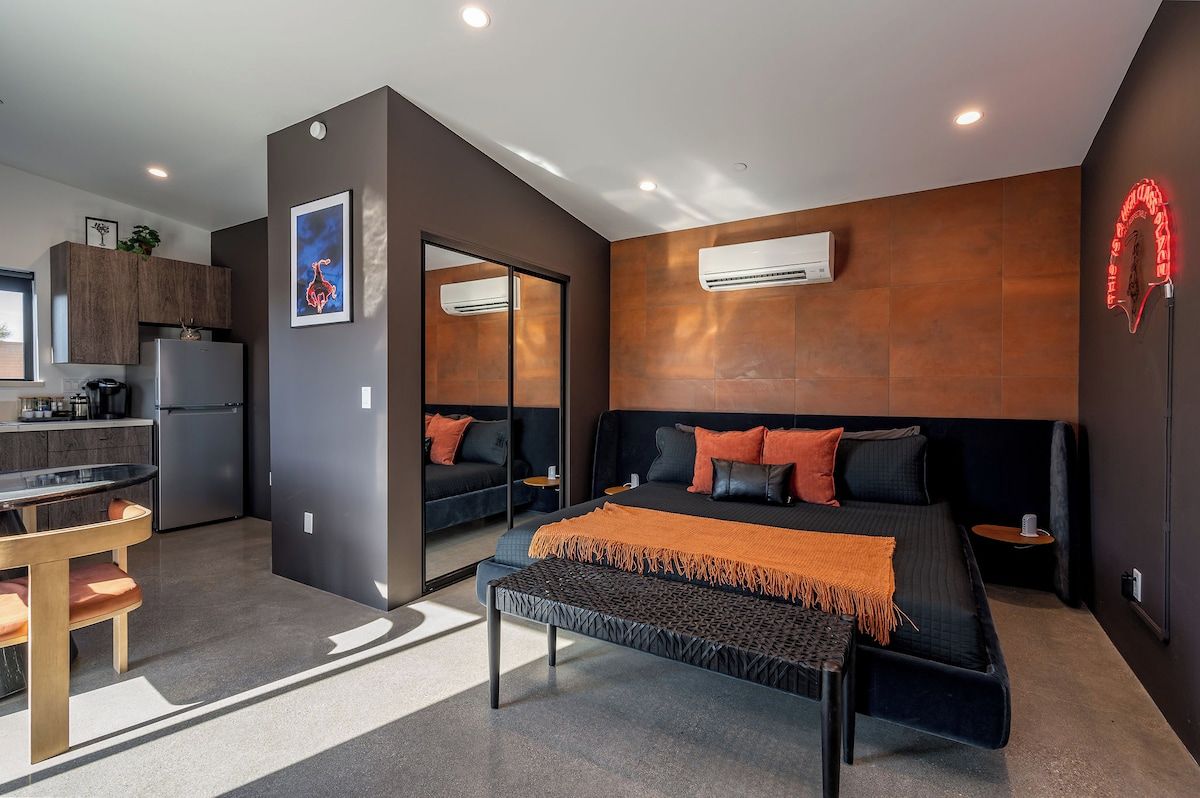 Une chambre à coucher moderne avec un grand lit, un banc et une petite table.