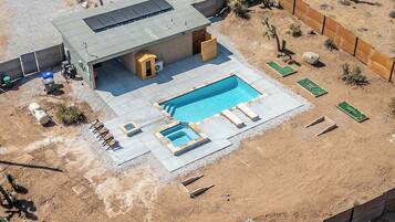 Une maison moderne dotée d’une piscine, d’un espace salon extérieur et d’une cour clôturée.