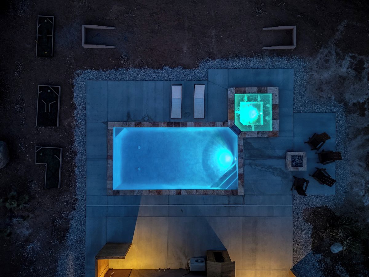Une piscine sur le toit, dotée d’un jacuzzi, entourée d’espaces de détente et d’un foyer extérieur.