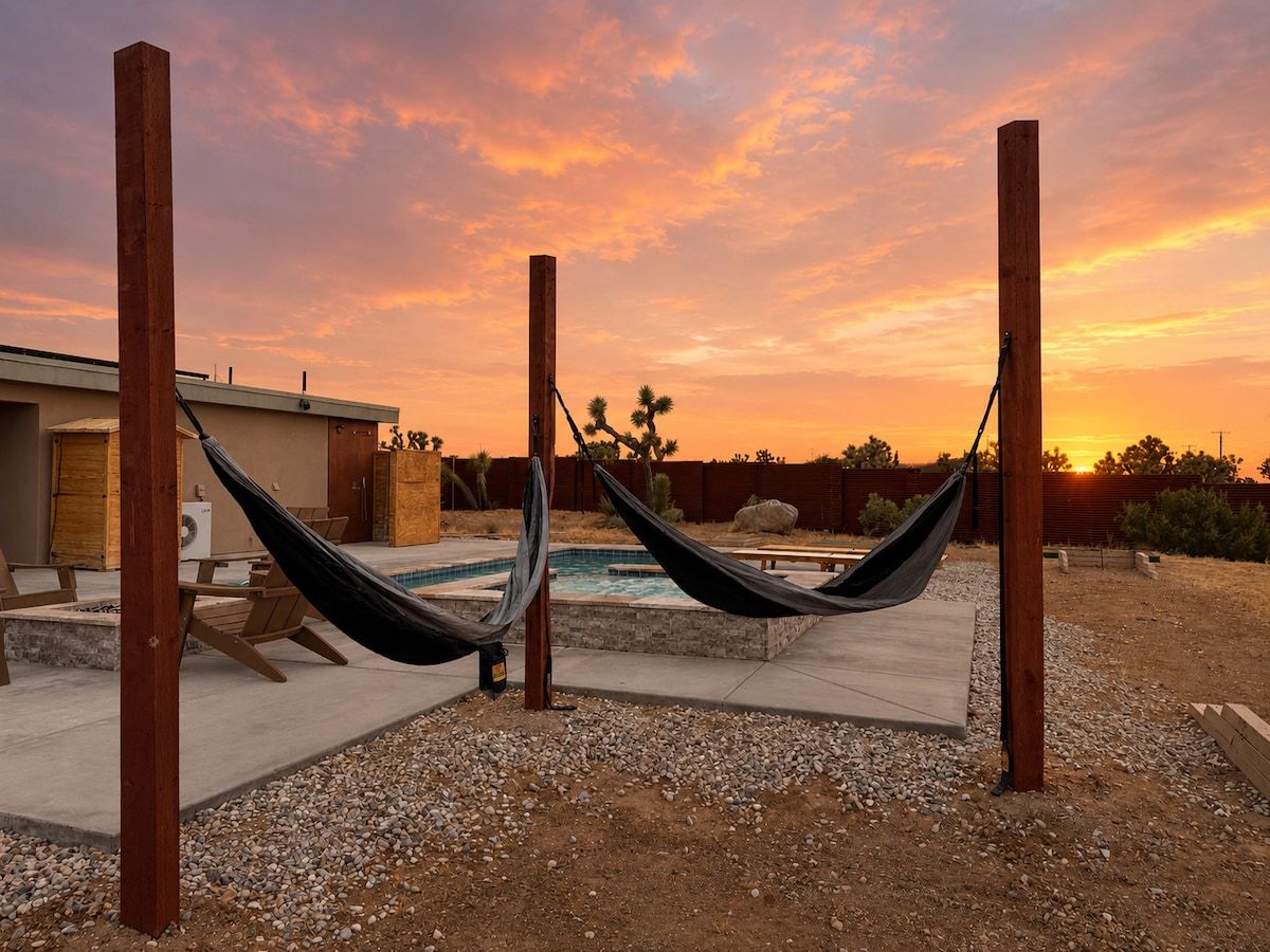 Un hamac installé dans un jardin, avec une piscine et une maison en arrière-plan.