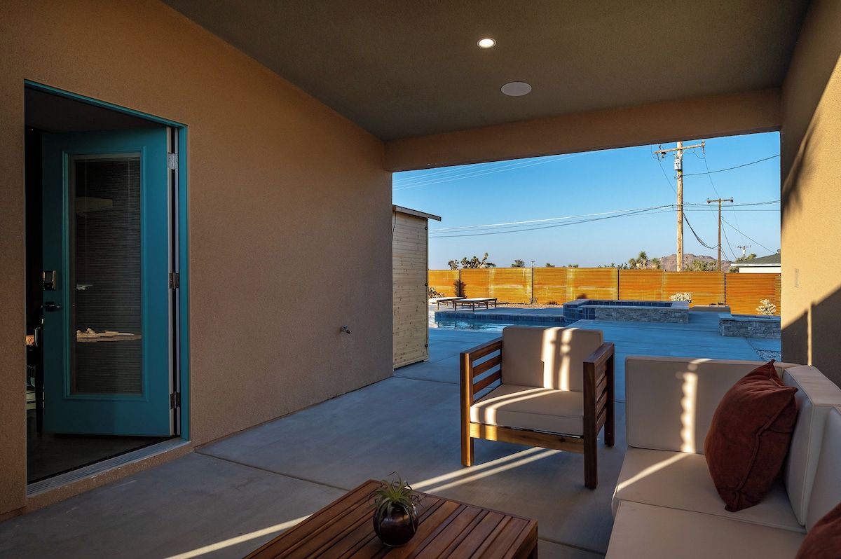 Shaded patio off the tiny home with cushioned seating overlooking the pool