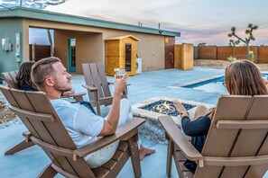A poolside area with outdoor seating and a fire pit.