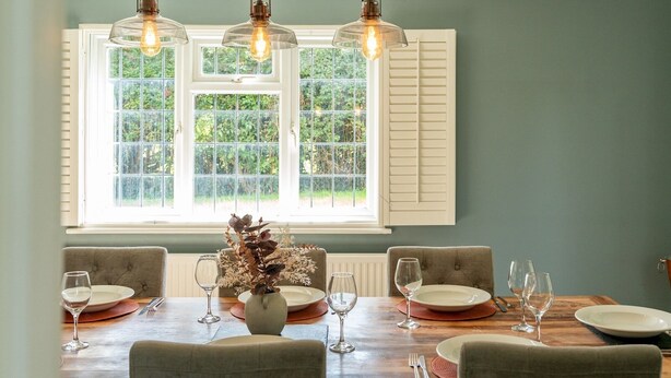 A dining area with a wooden table set for four, surrounded by upholstered chairs.