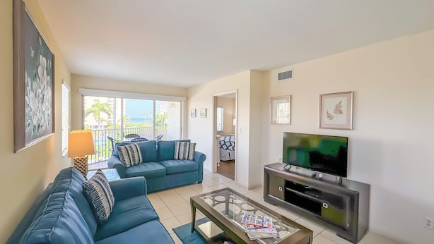 Una sala de estar con sofá, televisión y balcón con vistas.