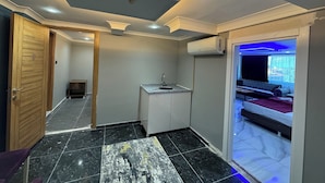 Una habitación de hotel compacta con kitchenette, baño y balcón con vistas.