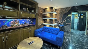 Un interior moderno con un gran acuario, un sofá azul y una mesa redonda.