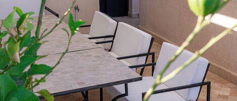 A patio area with a tiled table and white cushioned chairs.