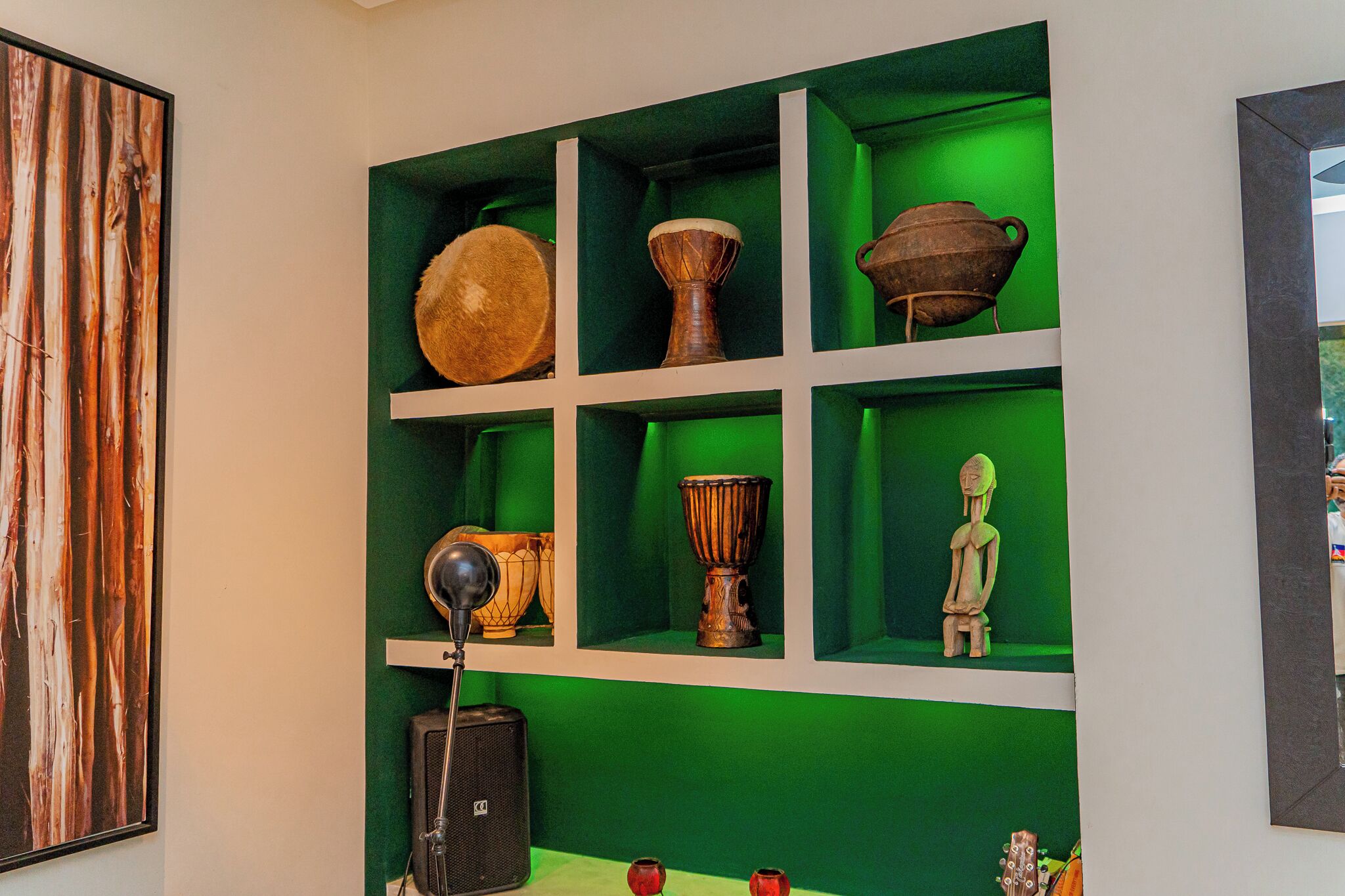 A room with a green wall and a shelf displaying various cultural artifacts.