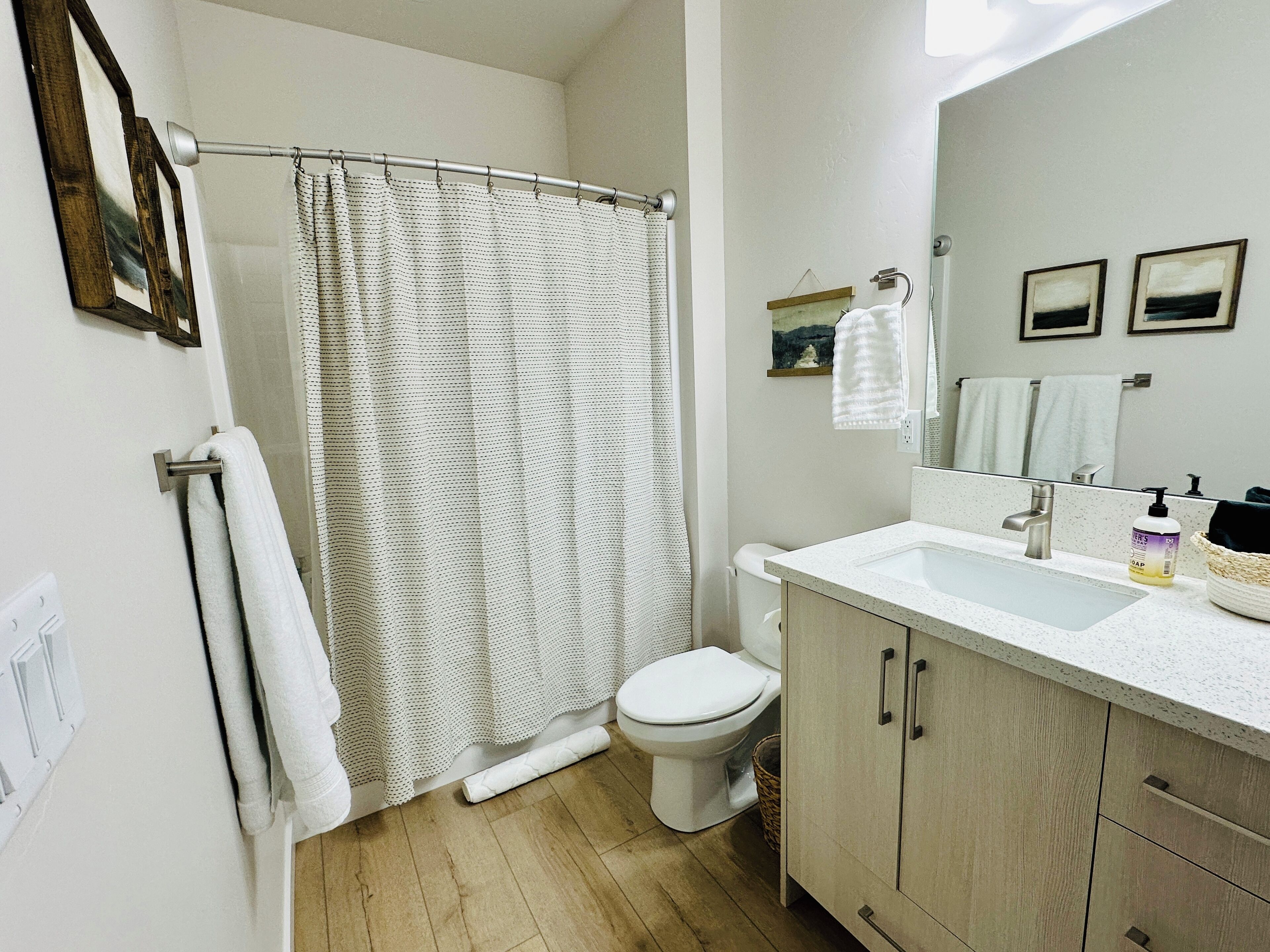Une salle de bain équipée d’un rideau de douche, de toilettes, d’un lavabo et d’un meuble de rangement.