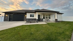 A modern two-story house with a stone facade, a black garage door, and a front porch with a bench. - Charming Modern Home Near All Magic Valley Attractions (Hollister)