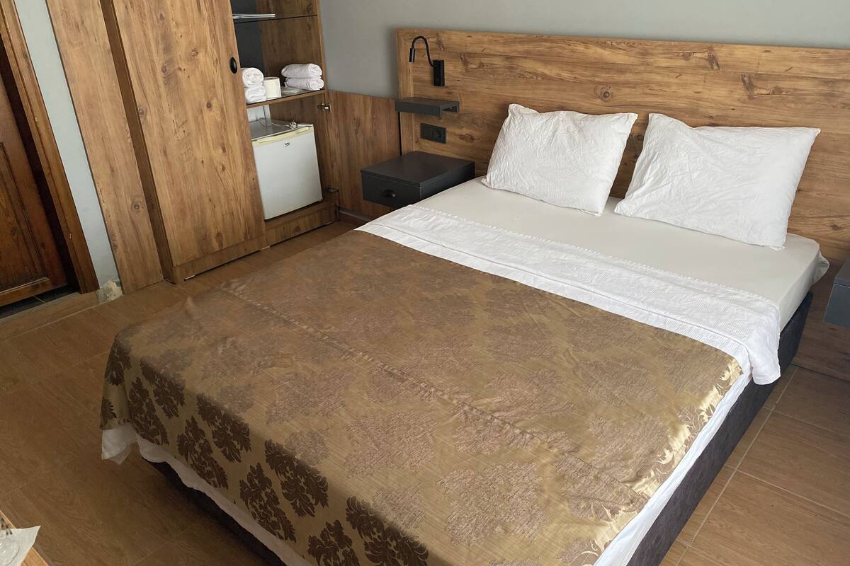 A bedroom with a wooden headboard, a bed with white linens, a nightstand, and a wardrobe.