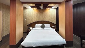 Une chambre d’hôtel avec un grand lit, une tête de lit en bois et une table de chevet avec un téléphone.