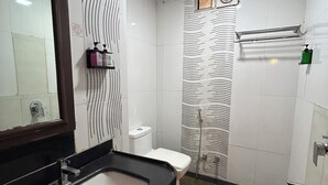 Une salle de bain avec un lavabo noir, des toilettes blanches et un espace douche.