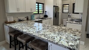 A modern kitchen with white cabinets, a granite countertop, and bar stools.