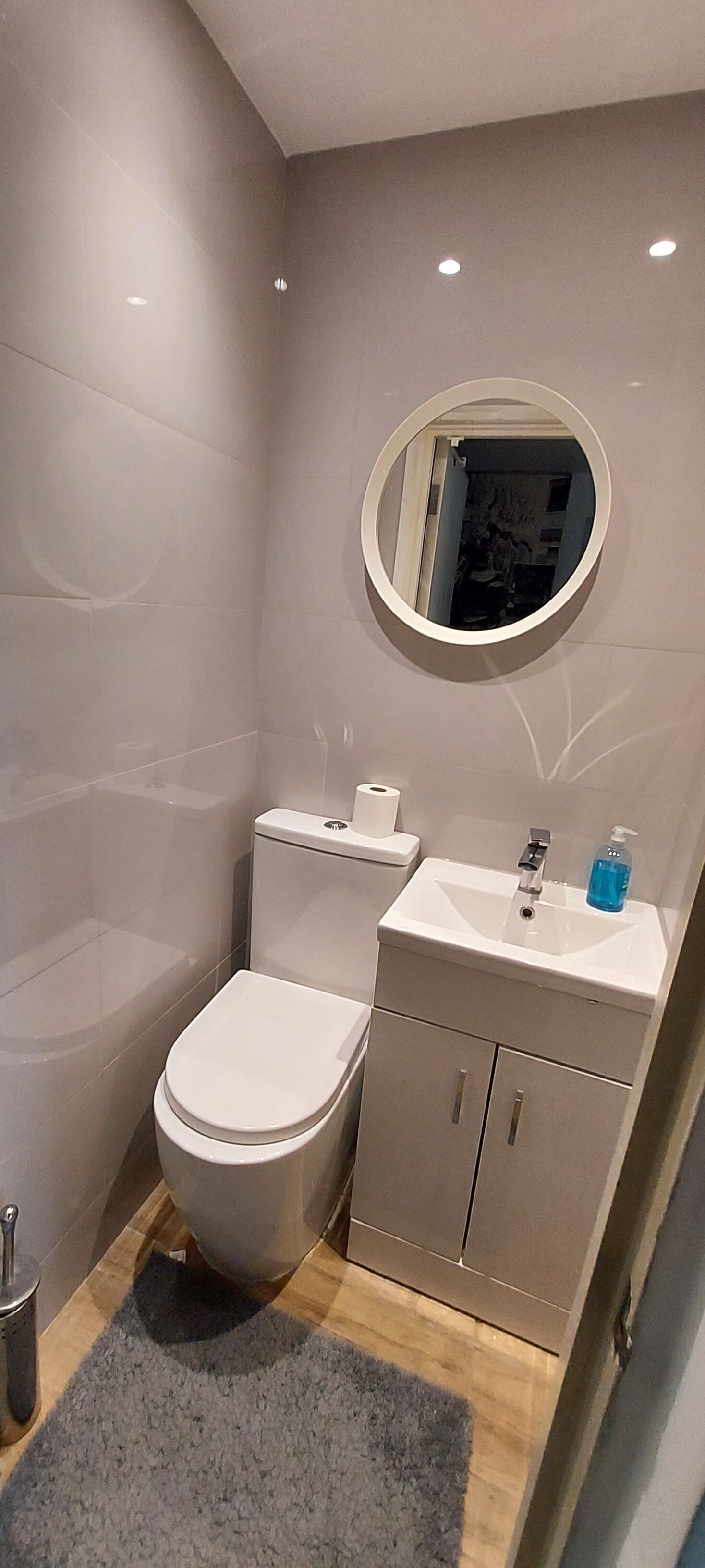Un baño moderno con inodoro, lavamanos y espejo.