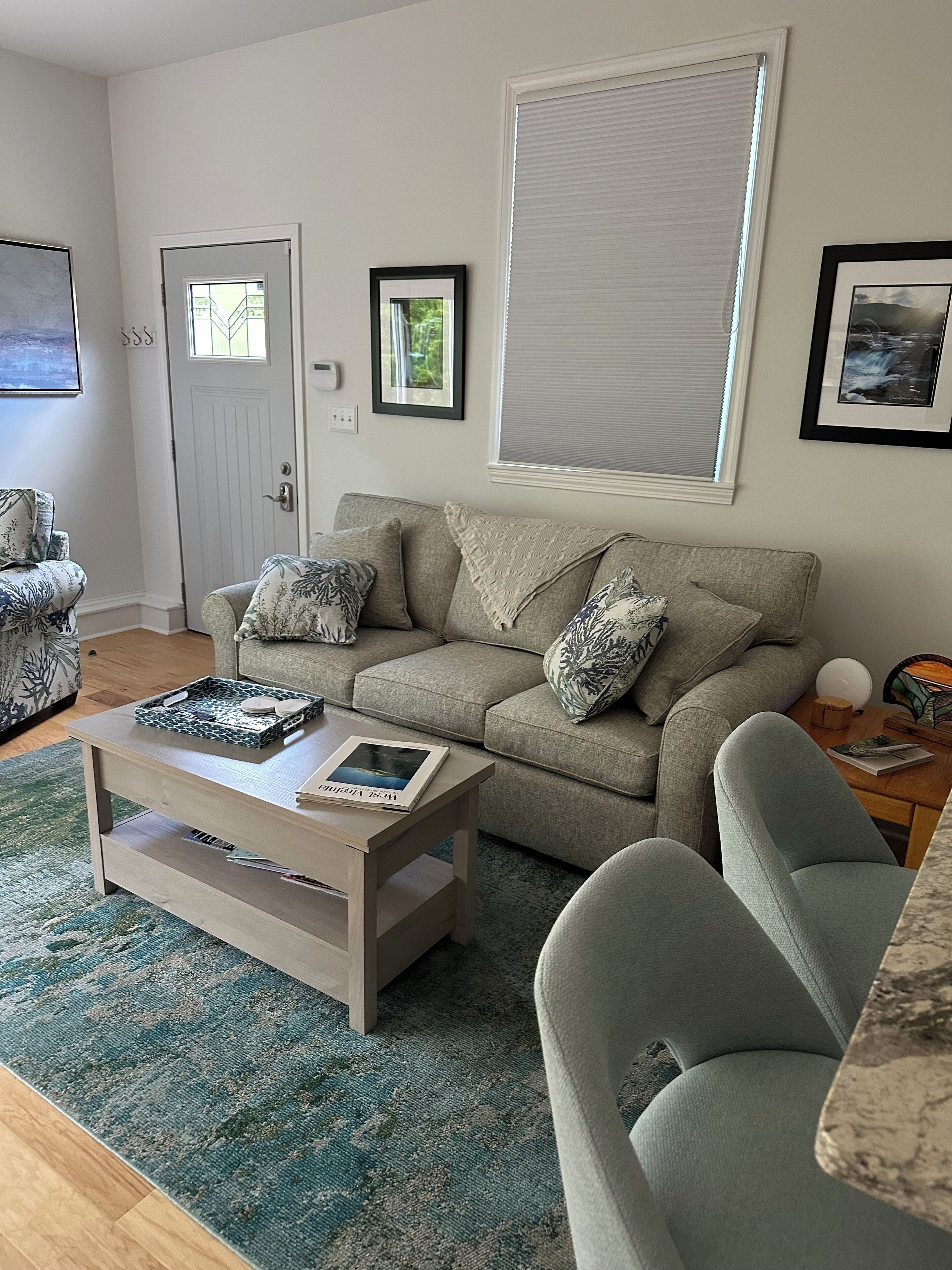 A living room with a grey sofa, a coffee table, a patterned rug, and a door with a window.