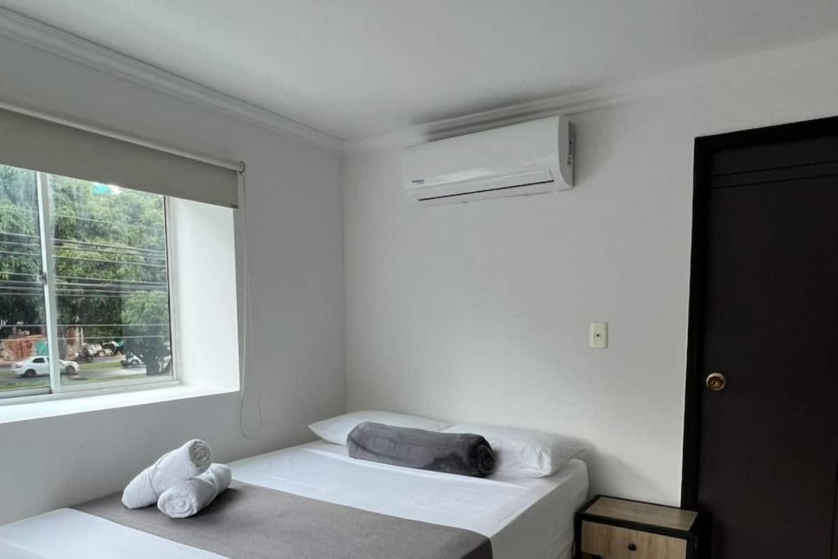 Un dormitorio con cama, ventana, puerta y equipo de aire acondicionado.
