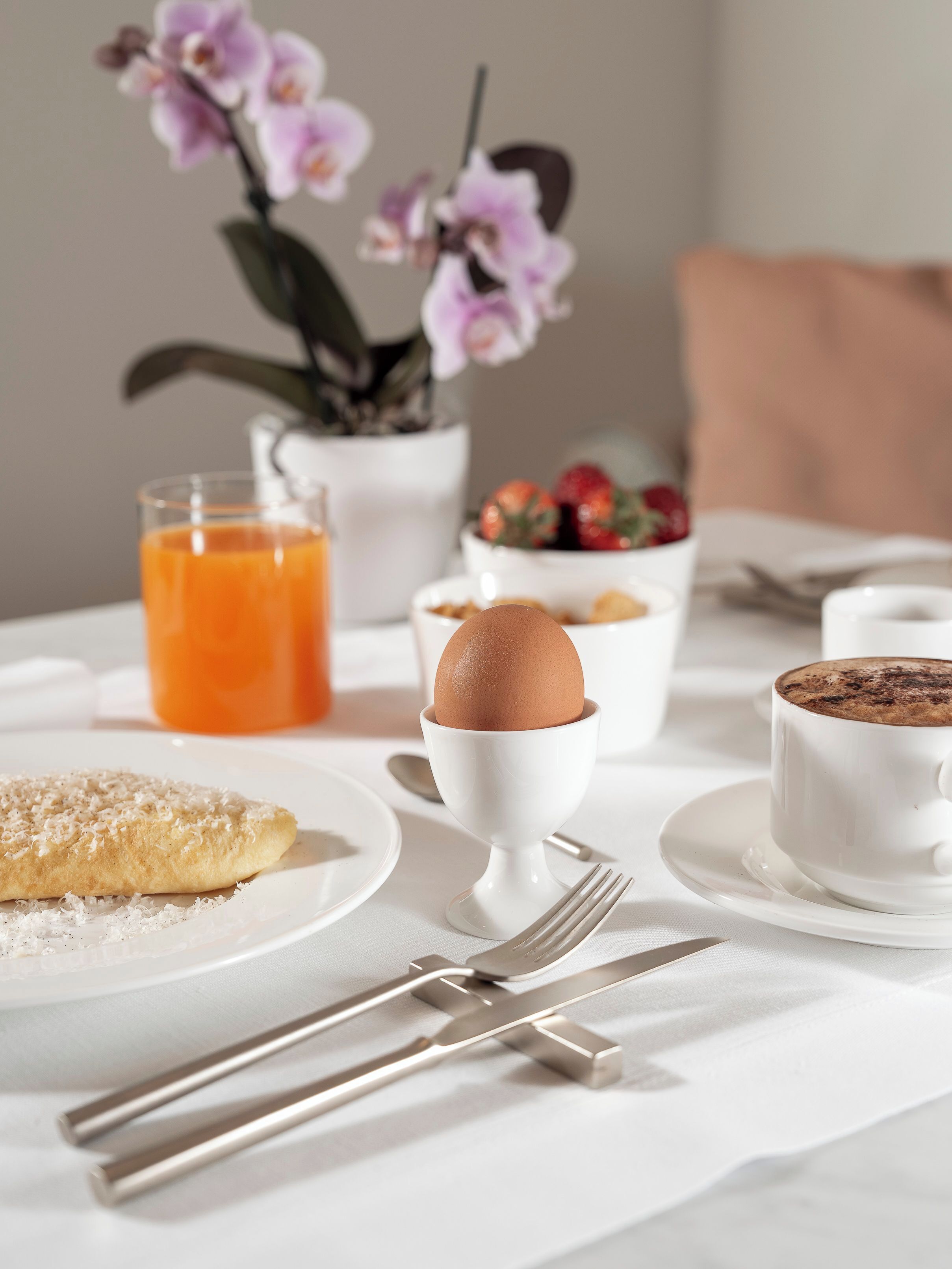 Un desayuno con tostadas, una taza de café, un bol de fruta y un vaso de zumo de naranja.