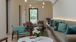 Eine moderne Lobby mit einer Couch, Stühlen, einem runden Tisch und einer Zimmerpflanze.