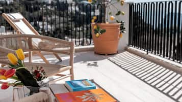 Un balcon avec un fauteuil en osier, une plante en pot et un livre intitulé « Capri Dolce Vita ».