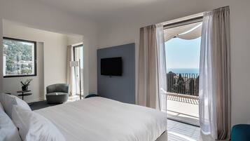 A modern hotel room with a large bed, a flat-screen TV, a balcony with curtains, and a city view.
