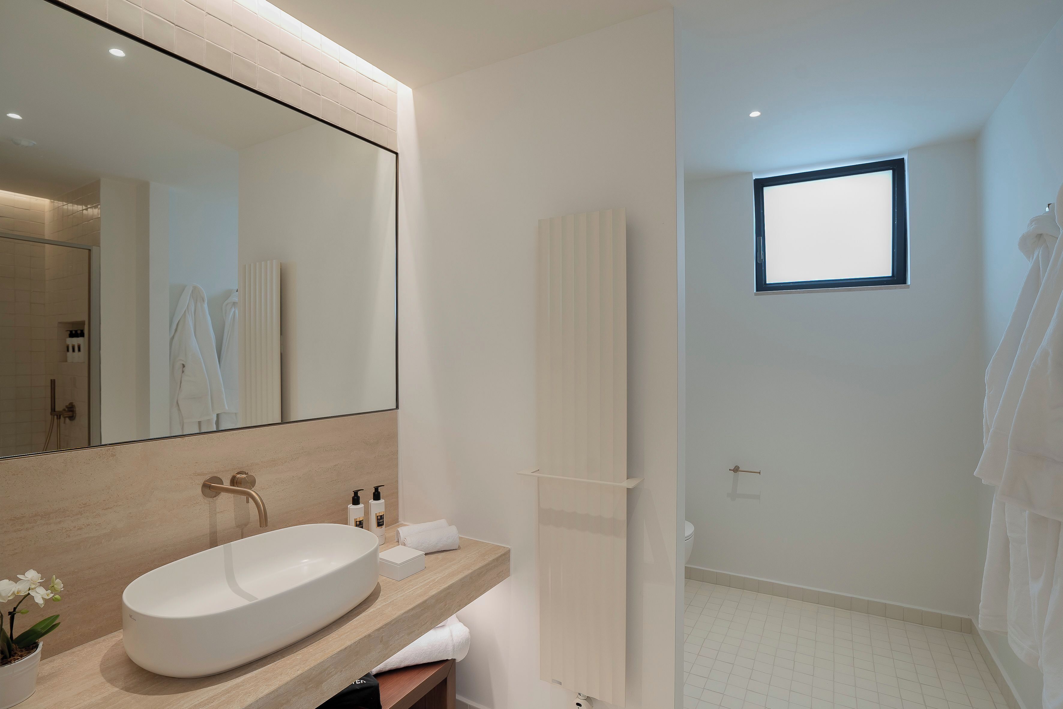 Un baño moderno con un espejo grande, un lavabo y una zona de ducha.
