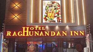 Entrada de hotel com uma grande placa iluminada que diz 'Hotel RagHunandanan Inn'.