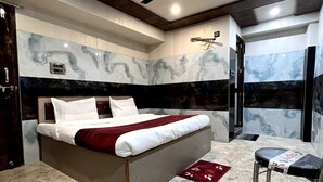 Quarto moderno com cama grande, piso de mármore, ventilador de teto e um pequeno banquinho.