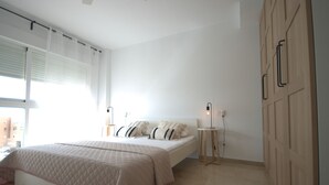 Un dormitorio con cama, mesitas de noche y un armario.
