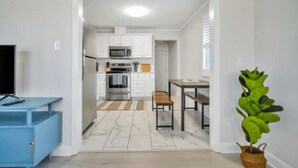 A modern kitchen with white cabinets, a microwave, and a dining area with a table and chairs. - 4BR/3BA Retreat - Perfect for Families & Groups (Tybee Island)