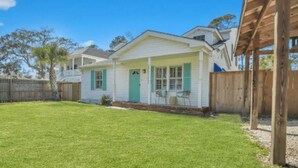 A single-story house with a front porch, a small front yard, and a wooden fence. - 4BR/3BA Retreat - Perfect for Families & Groups (Tybee Island)