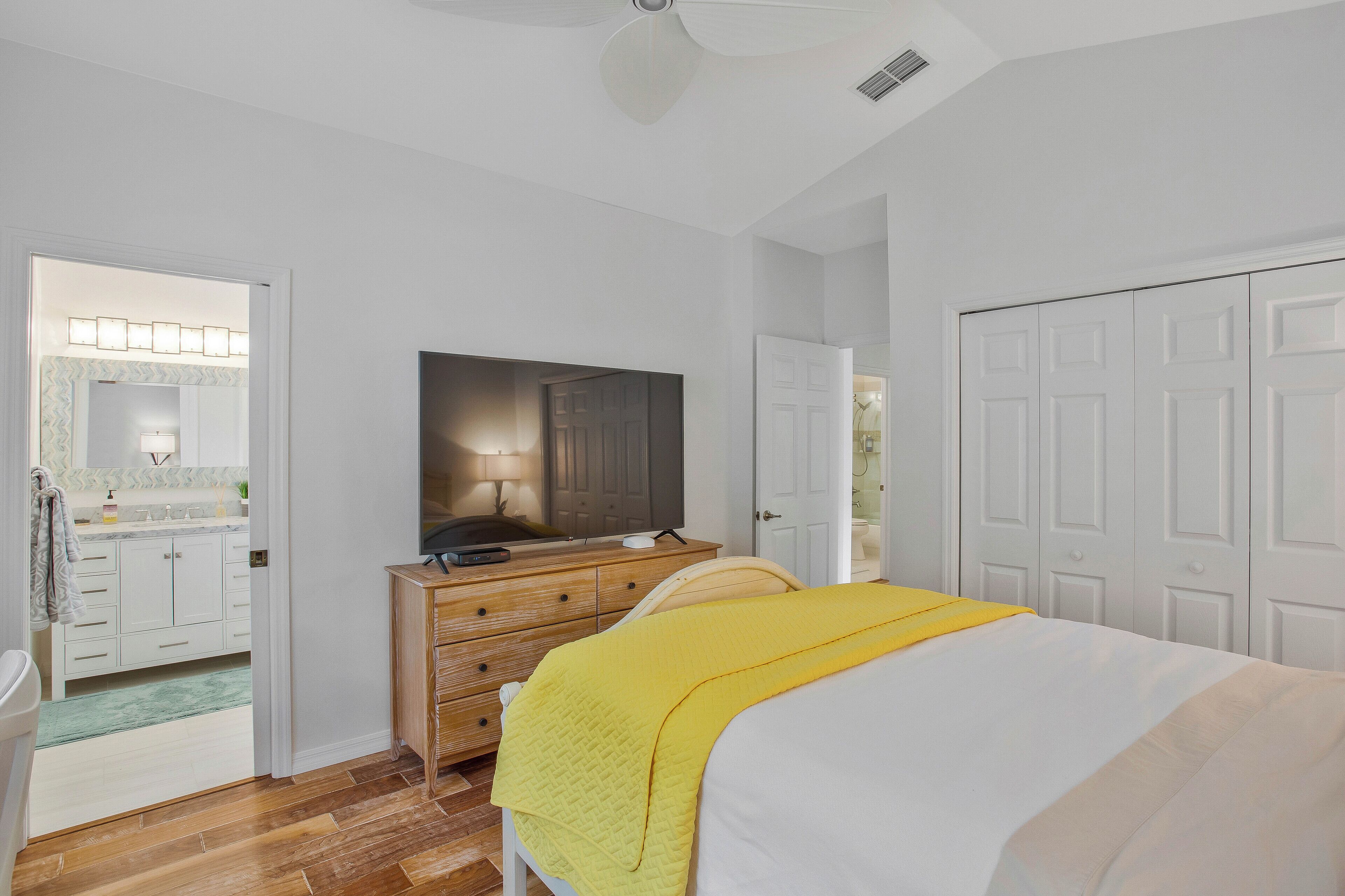 A bedroom with a bed, a dresser, a television, and a door.