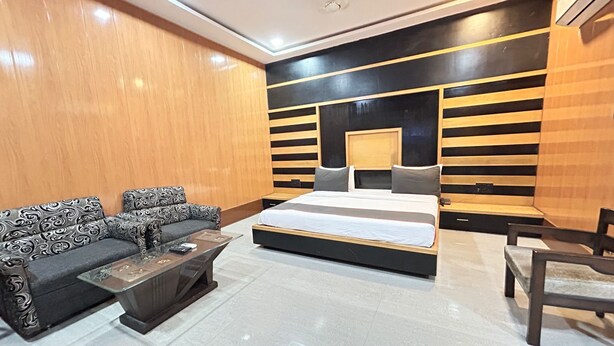 A modern bedroom with a large bed, a sofa, a coffee table, and a chair. - SwagStay Hotel Rahul Palace Nagpur (Nagpur)