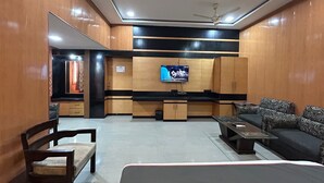 A modern living room with a flat-screen TV, wooden cabinets, a sofa, and a dining table. - SwagStay Hotel Rahul Palace Nagpur (Nagpur)