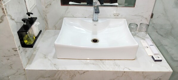 A bathroom with a white sink, a mirror, and a soap dispenser on a marble countertop. - The Royal Palace (Dewas)