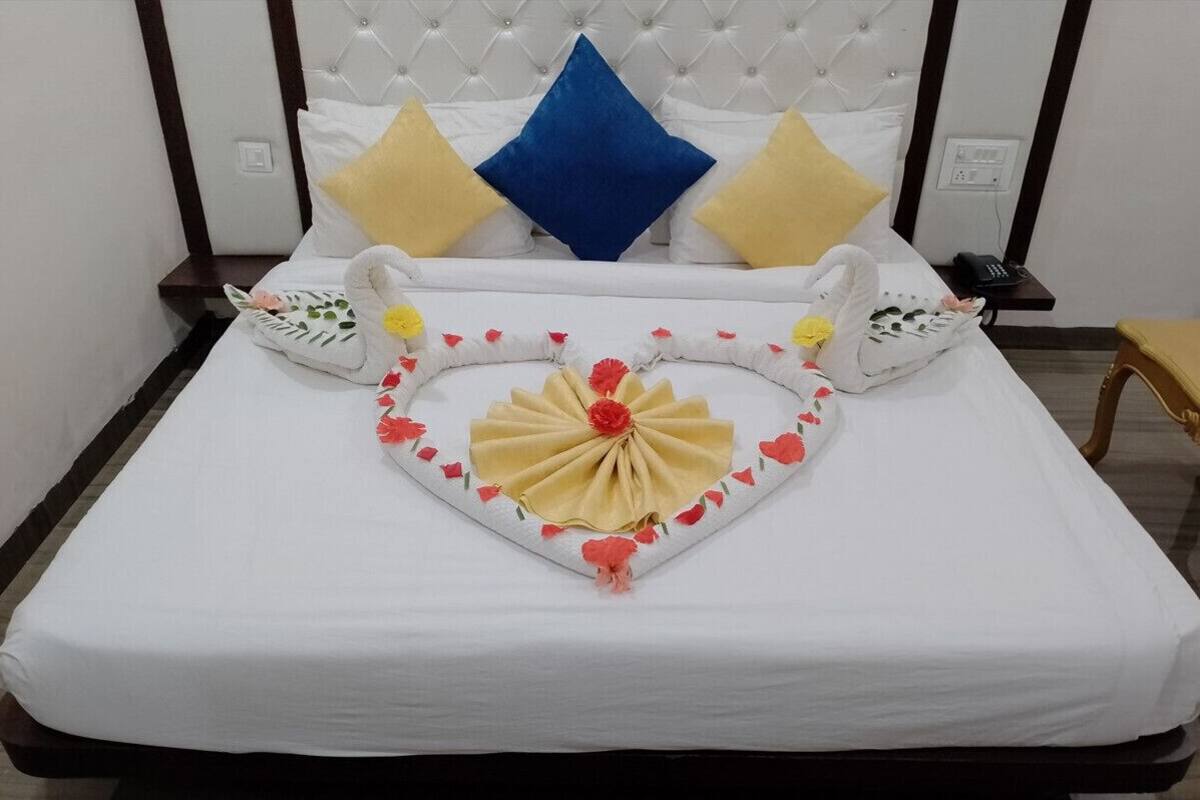 A neatly made bed with a heart-shaped centerpiece and decorative pillows.
