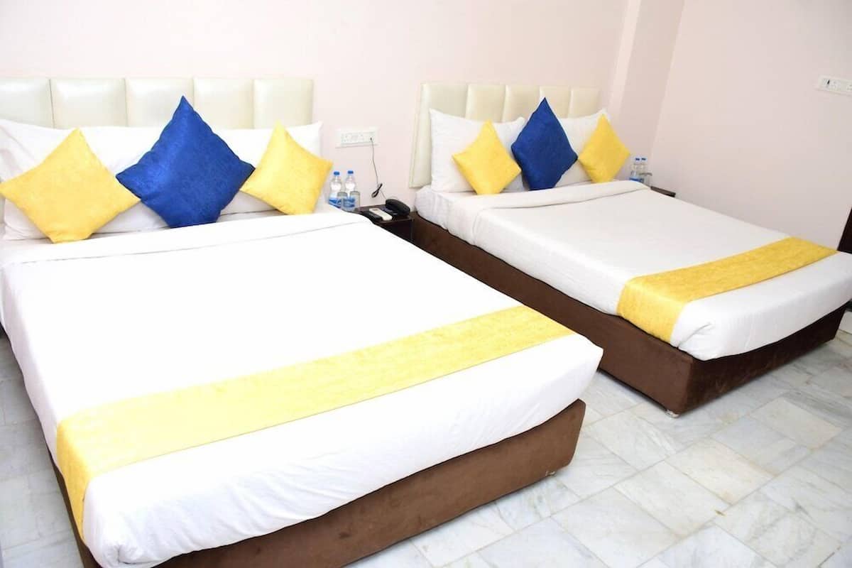 Two twin beds with white and yellow bedding, blue and yellow pillows, and a brown headboard.