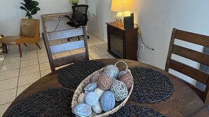 A dining area with a wooden table, four chairs, a basket of decorative balls, and a wall-mounted lamp.