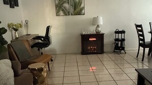 A living room with a sofa, a coffee table, a patterned rug, a side table with a lamp, and two framed pictures on the wall.