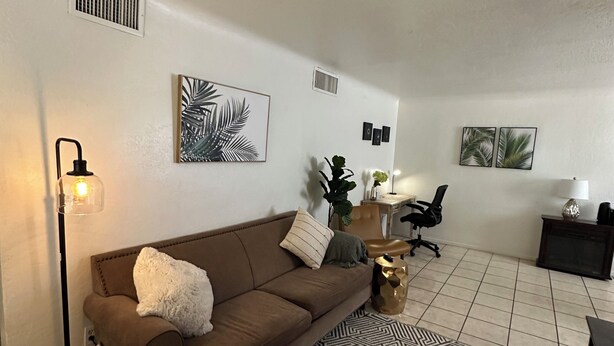 A living room with a brown sofa, a patterned rug, and a lamp.