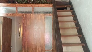 A wooden staircase with a glass panel and a flower wall at the top. - Hostal Españolete (Santa Marta)