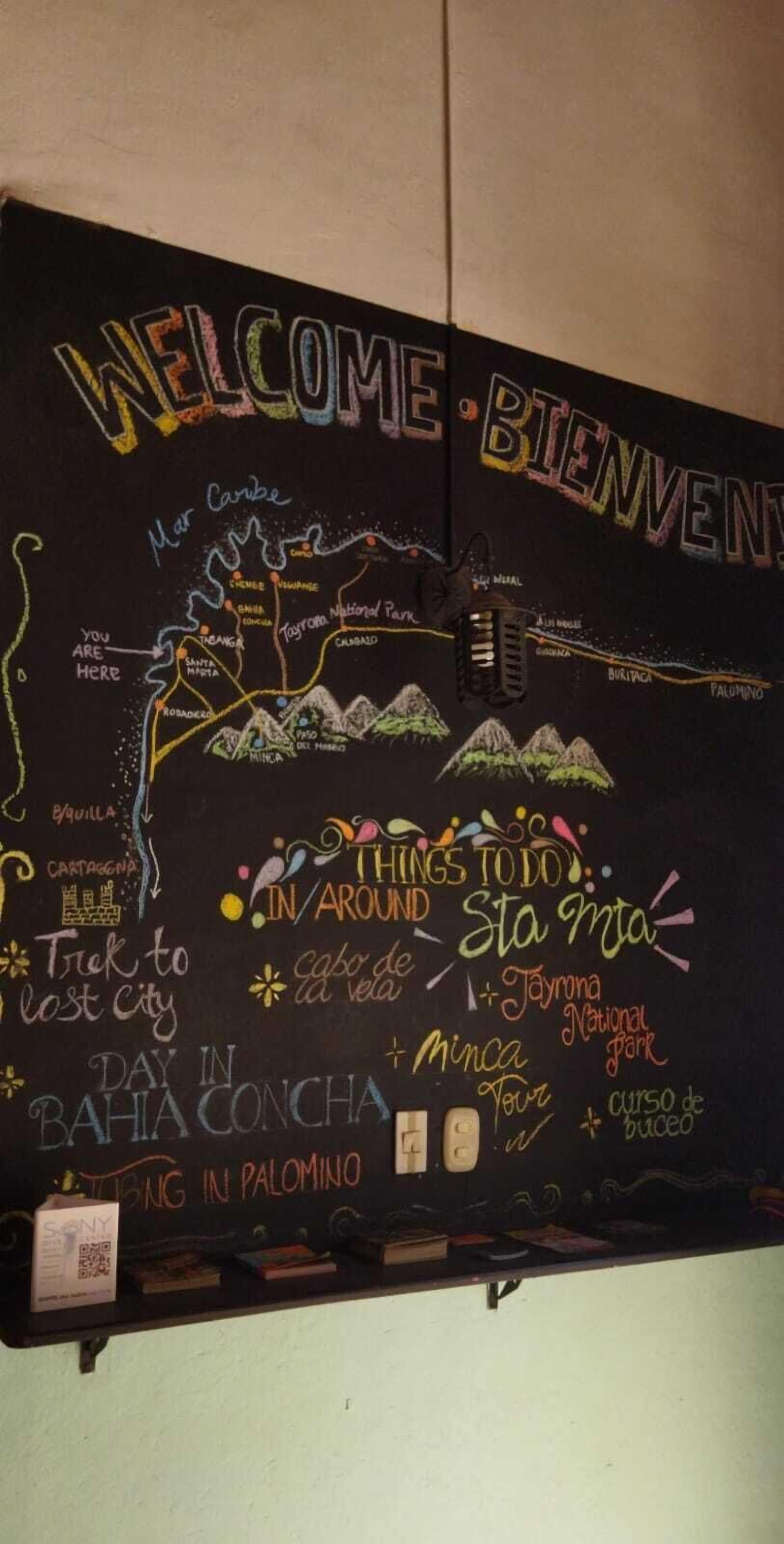 A blackboard with a map and travel-related text, including "Welcome," "Things to do in Sta. Marta," and "Day in Bahia Concha."