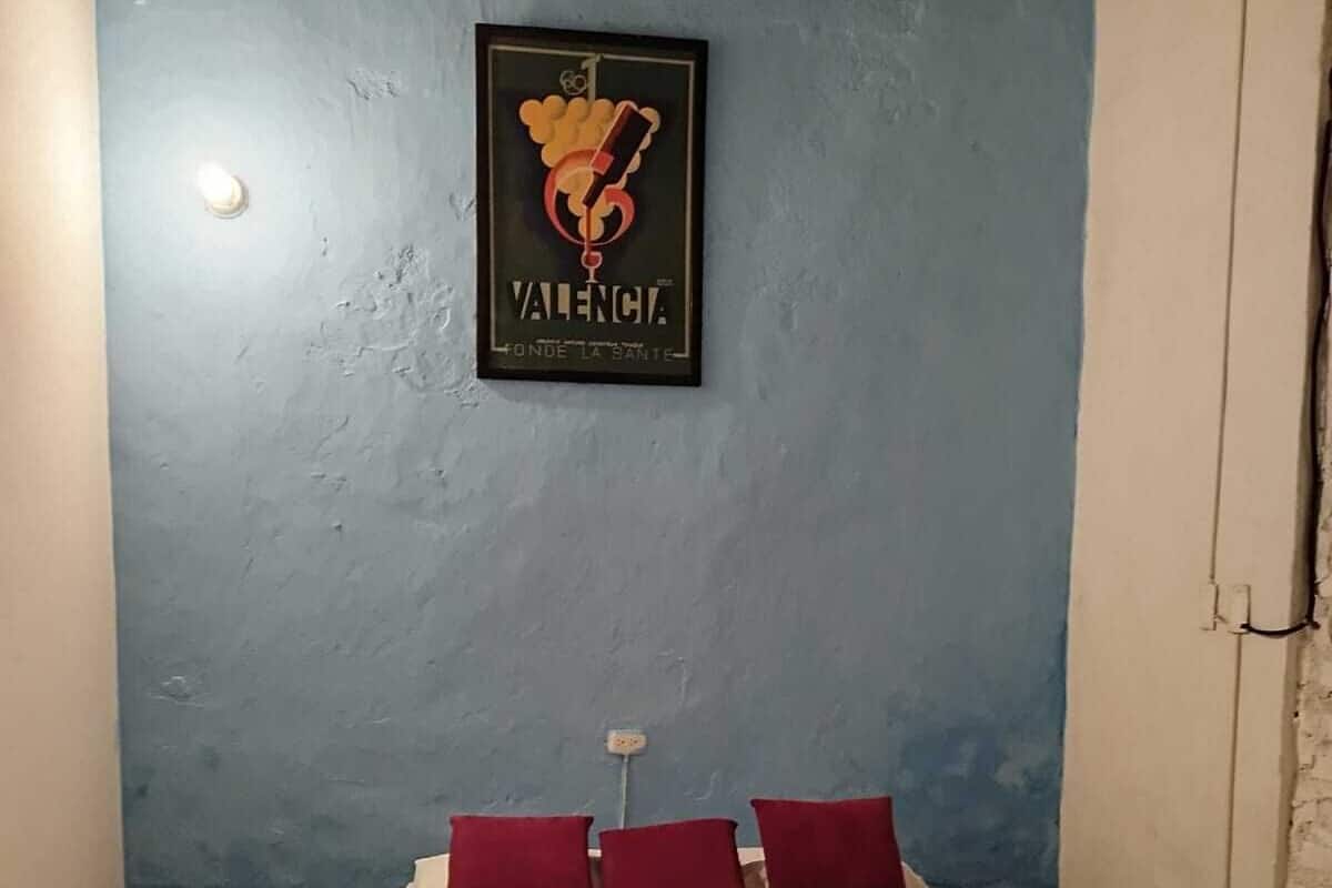 A bedroom with a bed, pillows, a nightstand, a wall-mounted picture, and a patterned floor.