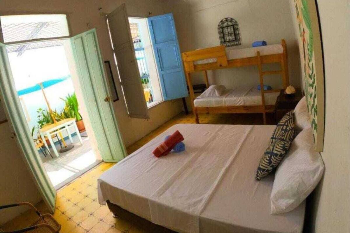 Una habitación con una cama individual, una litera, un ventilador de techo y una ventana con vistas.
