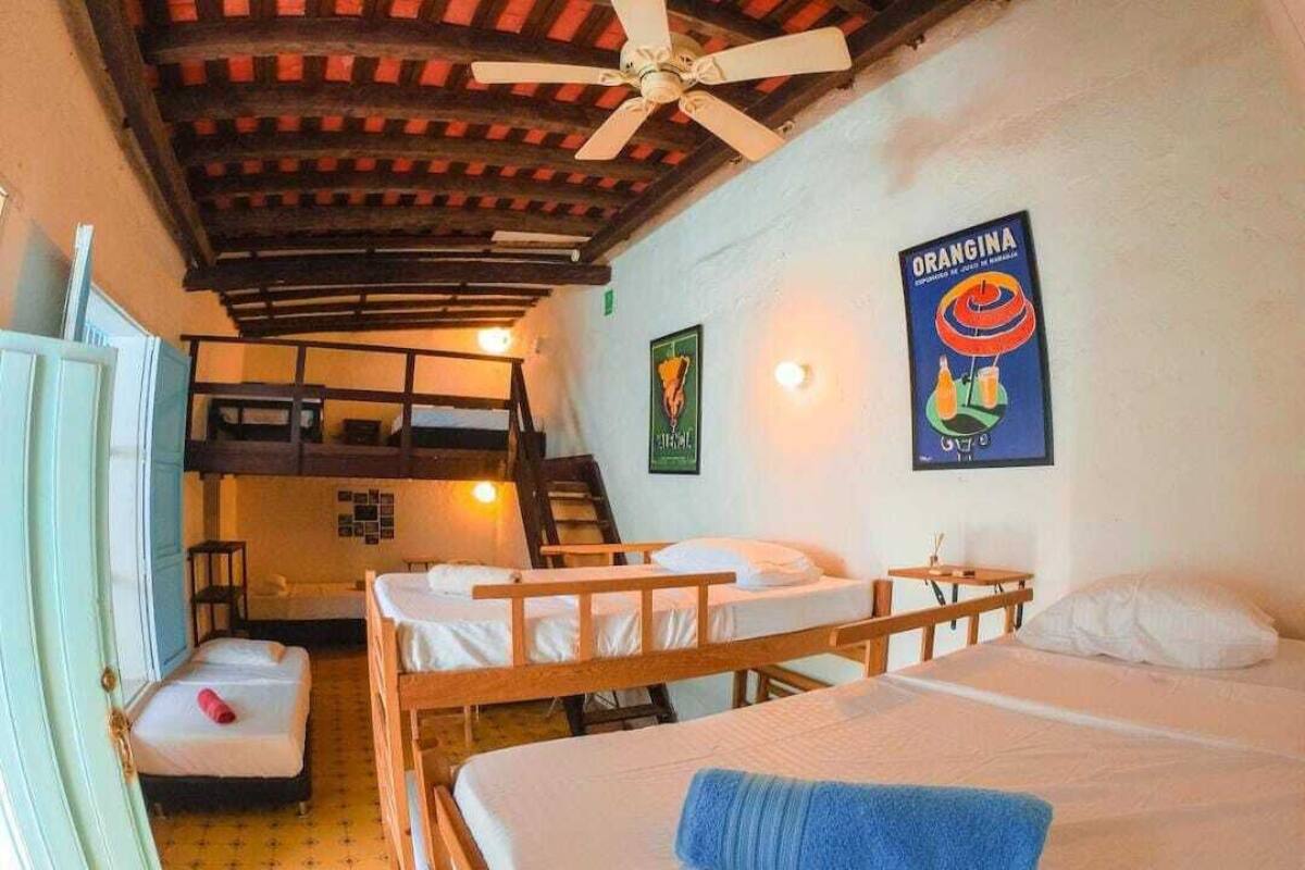 Una habitación con literas, ventilador de techo y un cartel en la pared.