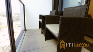 A balcony with wicker furniture, a view of the city, and a logo 'ITISTAYZ'. - Modern 1Bd Woden | Free Parking | Professionals (Phillip)