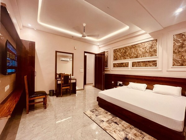 Une chambre d’hôtel moderne équipée d’un grand lit, d’un bureau avec une chaise, d’une télévision et d’un ventilateur de plafond.