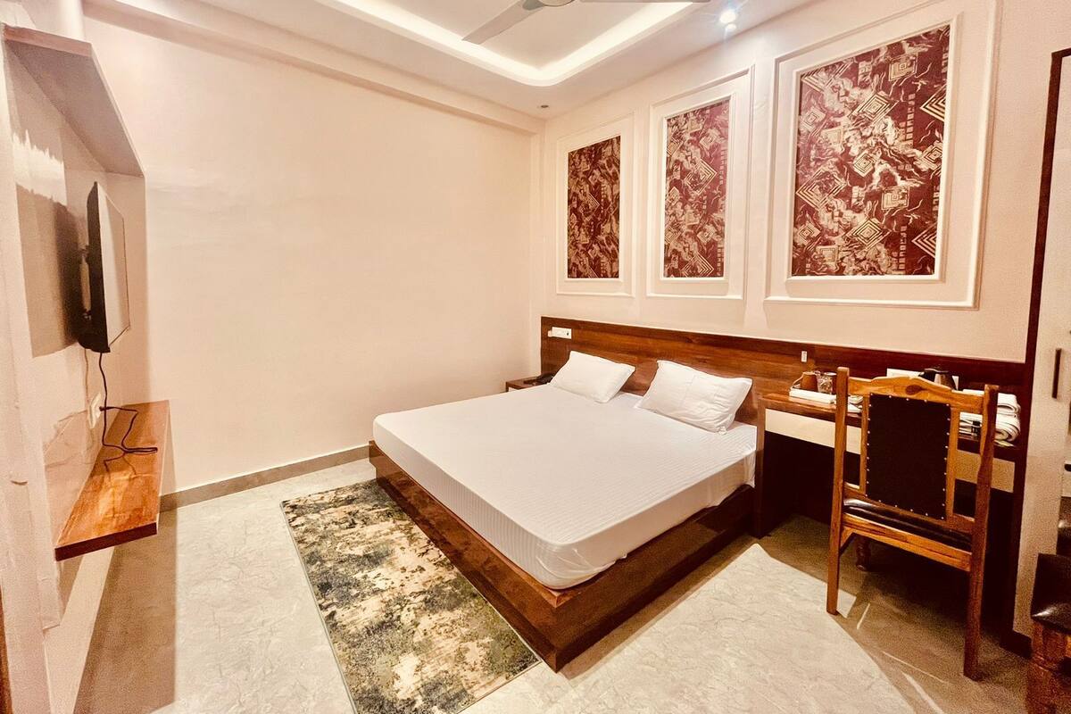 Une chambre à coucher comprenant un lit, une table de chevet en bois, une chaise et un ventilateur de plafond.